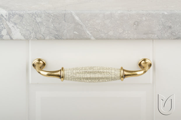 Mâner mobilier Tulip Country 128 – alamă antichizată + porțelan bej, efect crăpat, interax 128 mm, L138 mm