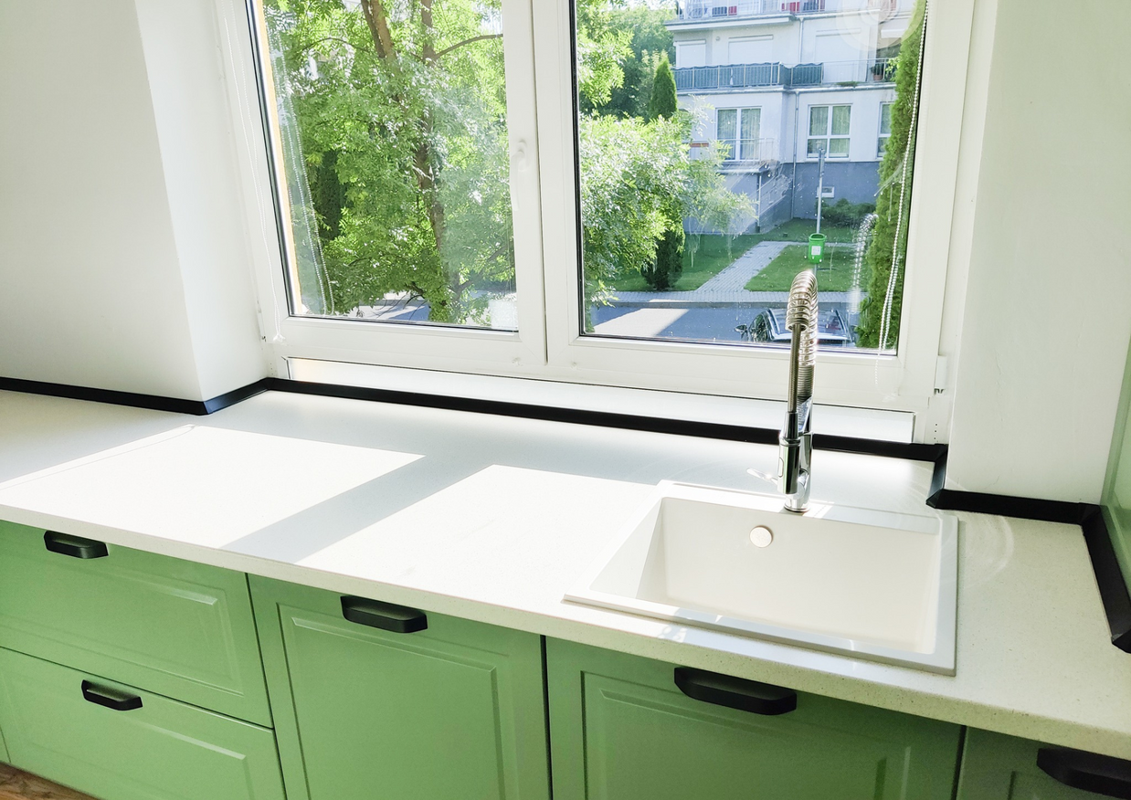 Mobila bucătărie fabricată la comandă de NORVINIA cu blat în L, cu îmbinare invizibilă, blat și glaf geam din același material, mobilier din MDF termoformat