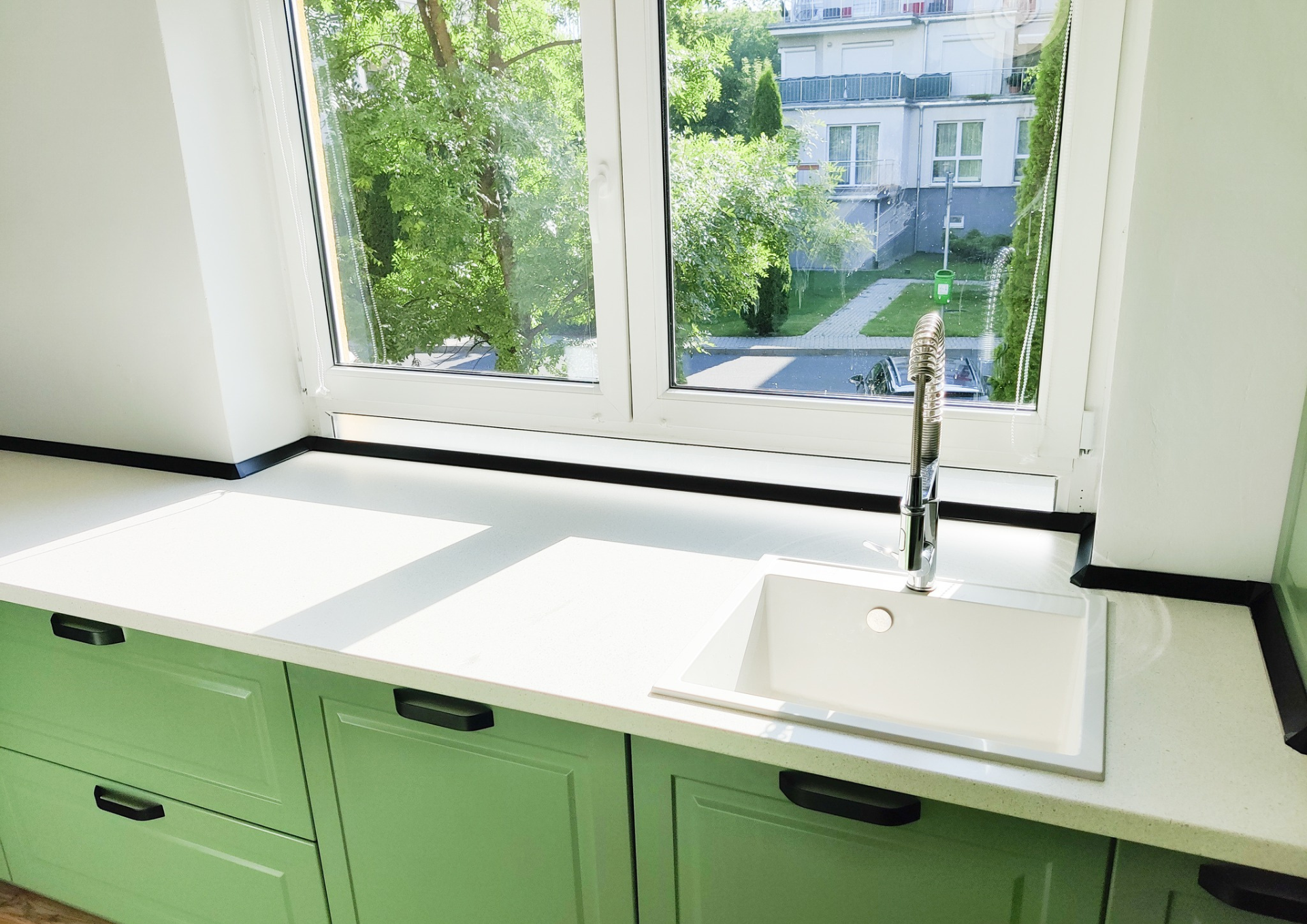 Mobila bucătărie fabricată la comandă de NORVINIA cu blat în L, cu îmbinare invizibilă, blat și glaf geam din același material, mobilier din MDF termoformat