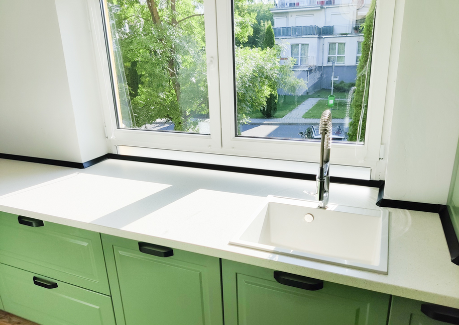 Mobila bucătărie fabricată la comandă de NORVINIA cu blat în L, cu îmbinare invizibilă, blat și glaf geam din același material, mobilier din MDF termoformat